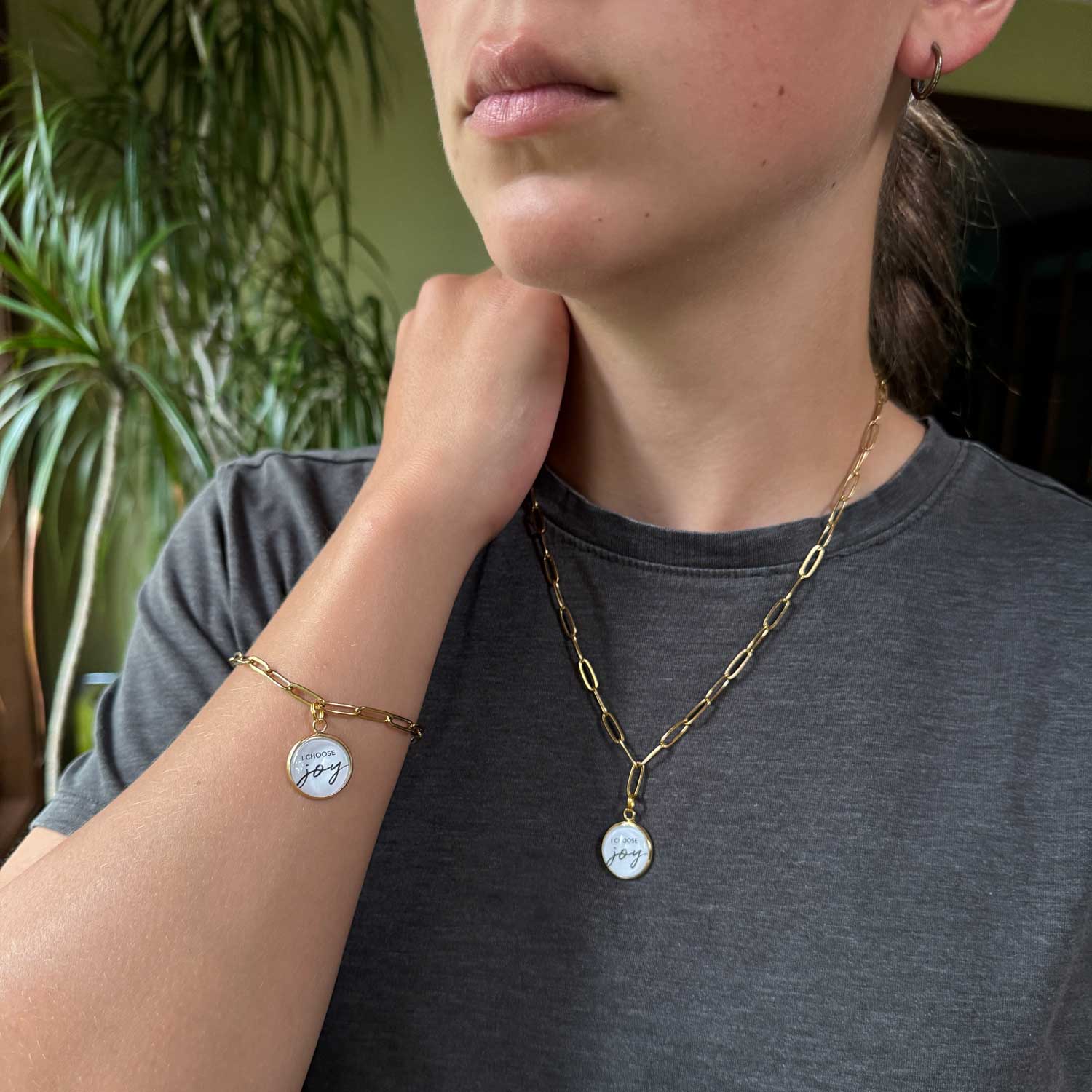 Model wearing an "I Choose Joy" Paperclip Chain Scripture Pendant Necklace and Charm Bracelet Jewelry Set, Gold